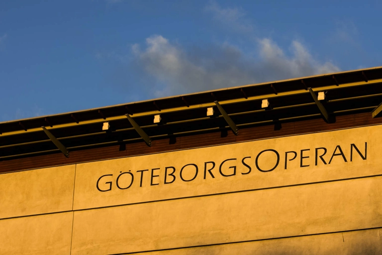 Översta delen av Göteborgsoperans fasad, upplyst i morgonsolen. Ordet "GöteborgsOperan" syns skrivet på fasaden.
