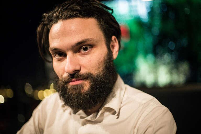 En porträttbild av någon som sitter och tittar in i kameran.