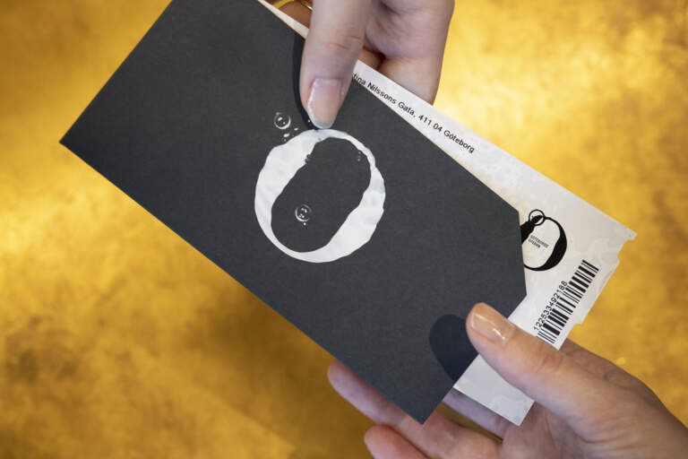 Närbild av en hand som skickar biljetter över biljettkassa disken till en annan hand.