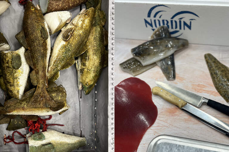 Rekvisita av flera hela samt delar av fisk som ligger på en skärbräda med knivar och scenblod, samt i frigolitlådor med is.
