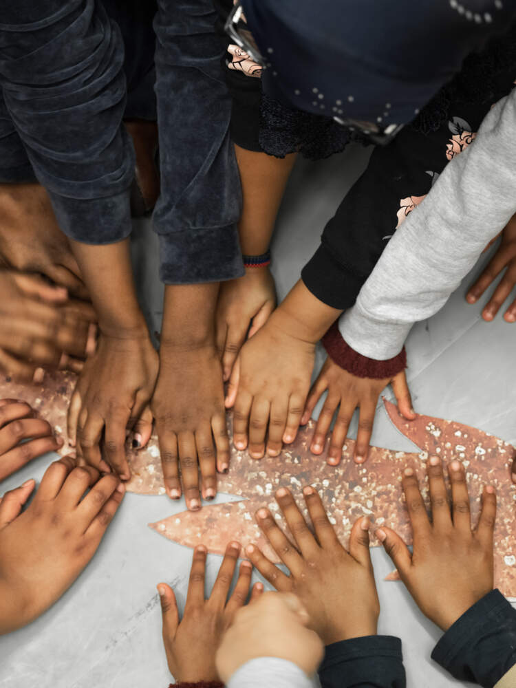 En grupp barnhänder sträcker sig ut med palmerna vilande platt på ett tecknat vargsvans som ligger på golvet.
