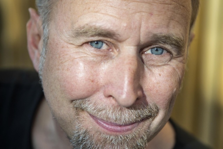 En porträttbild av någon som sitter och tittar in i kameran.