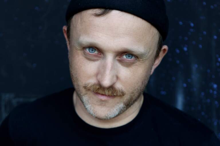 En porträttbild av någon som står och tittar in i kameran.