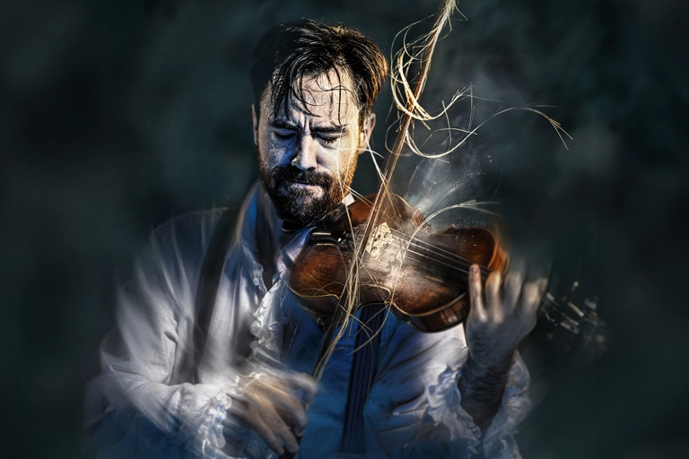 En svettig violinist står i rampljus och spelar så intensivt att hans armar är suddiga. Några hårstrån har lossnat på stråken