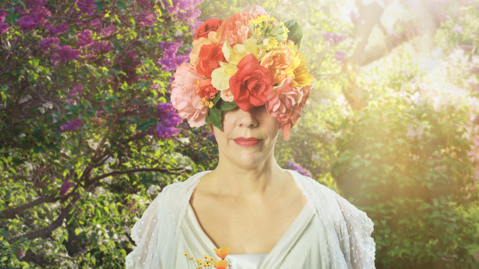 En person som bär en huvudbonad täckt av färgglada blommor står bland blommor i en solig, frodig trädgård.