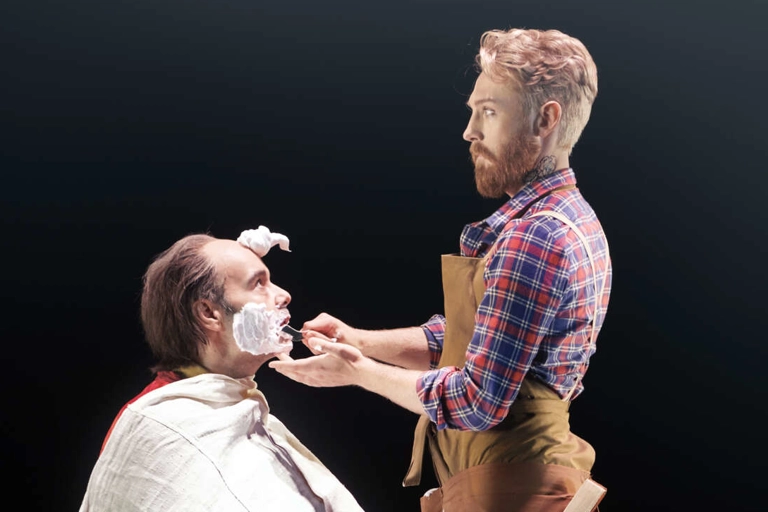 Figaro står framför Doktor Bartolo som sitter i en barberstol. Bartolo har raklödder på kinderna och en stor klick i pannan.