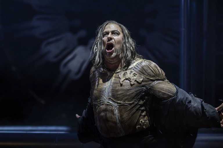 Holländaren sjunger med armarna utsträckta bakom sig. På hans kropp syns endast några hudtrasor kvar ovanpå muskulaturen.