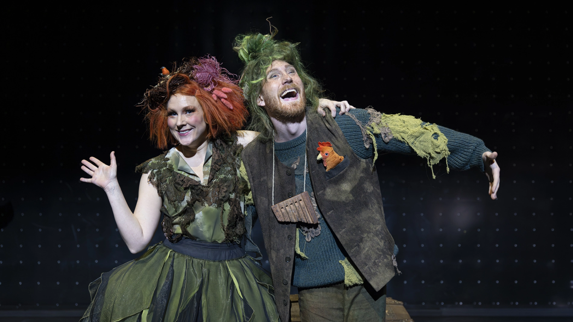 Papageno står med armen om Papagena, som vinkar. Båda ler.