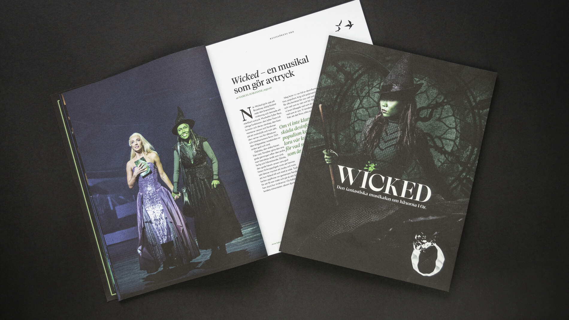Två program för musikalen Wicked ligger på svart bakgrund. Ett av programmen är öppet och det andra är stängt.