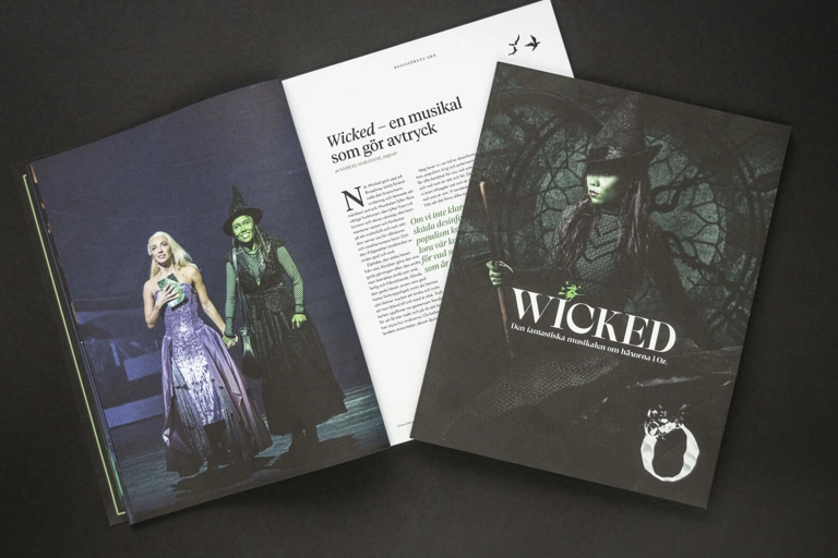 Två program för musikalen Wicked ligger på svart bakgrund. Ett av programmen är öppet och det andra är stängt.