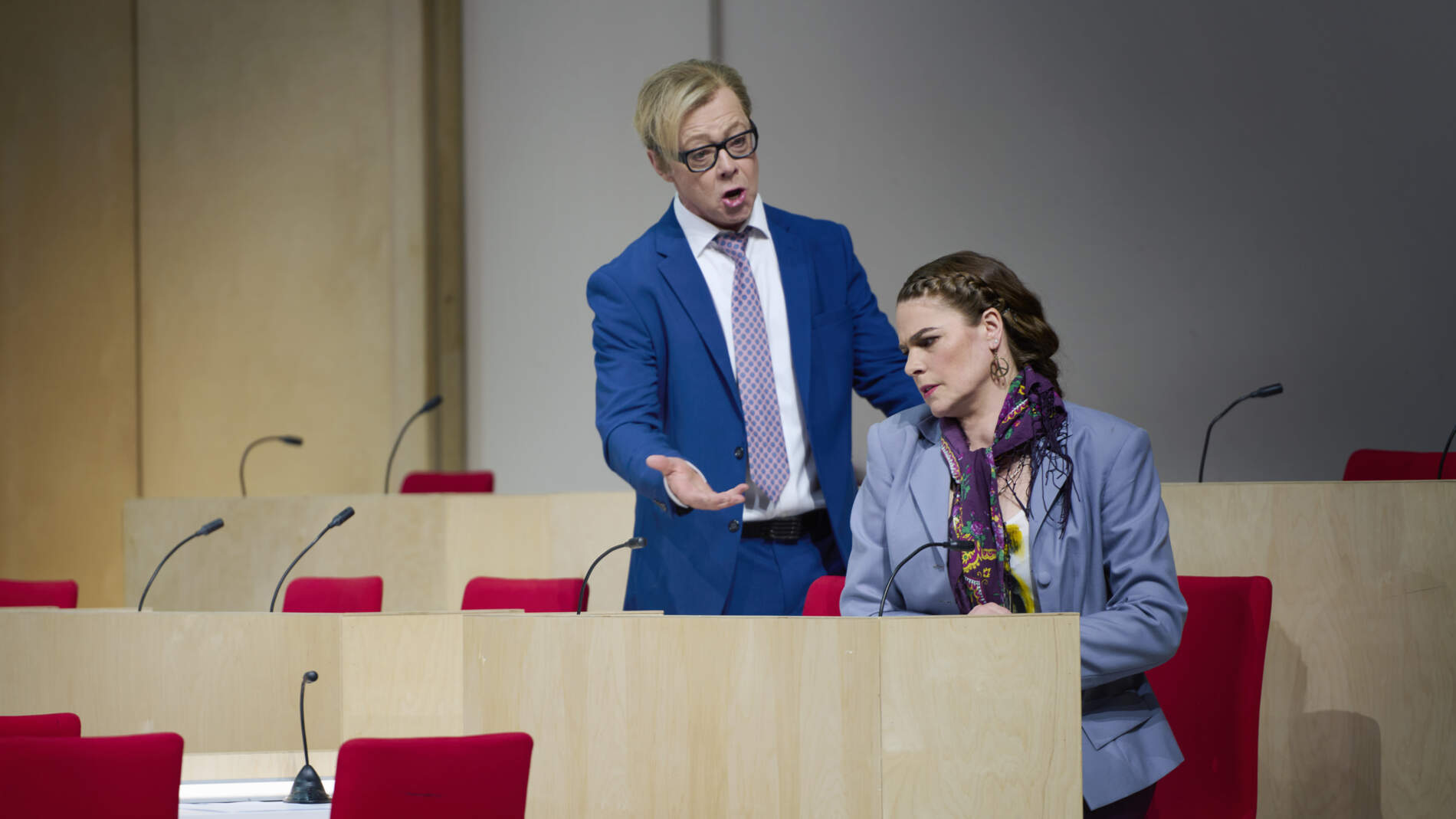 Ismael i kostym och slips står bakom Fenena och sjunger. Hon sitter på en stol i en politisk kammare med stolar i rader.