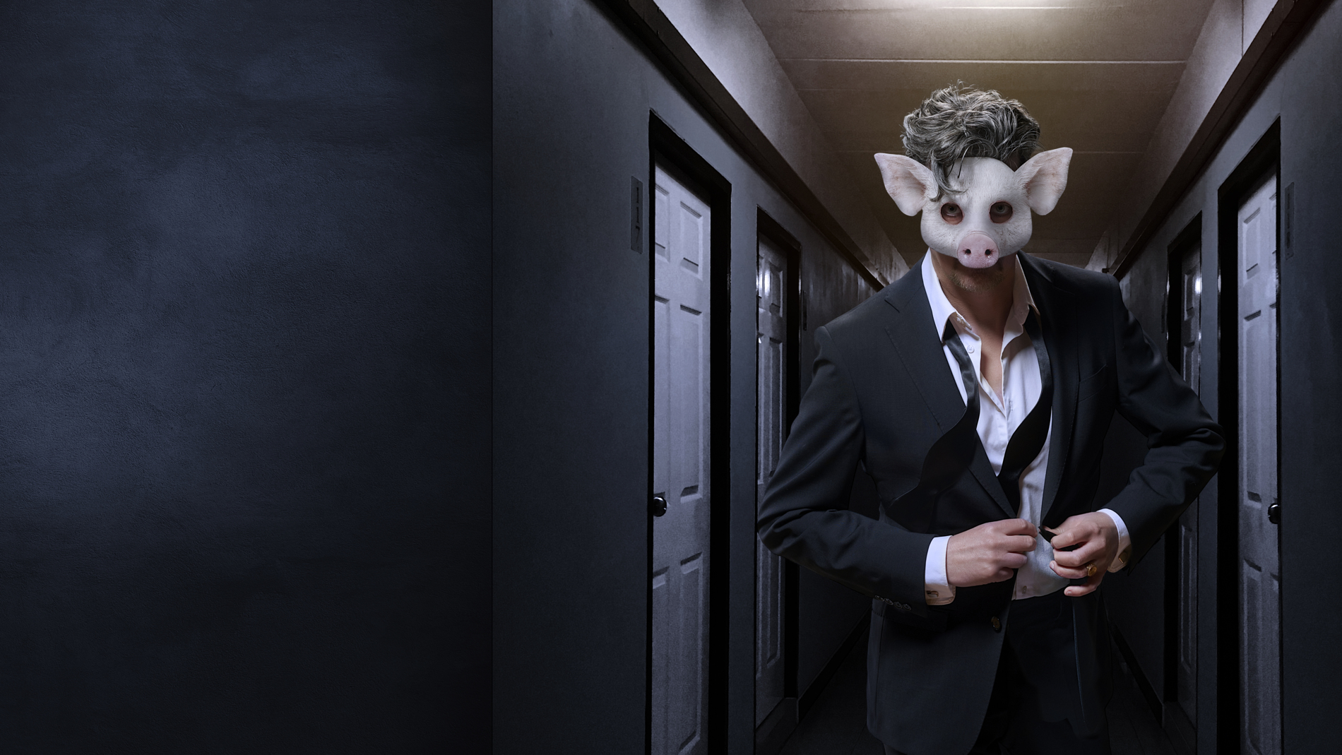 En man i kostym som bär en mask som ser ut som ett grishuvud går i en mörk korridor och knäpper ihop sin kavaj.