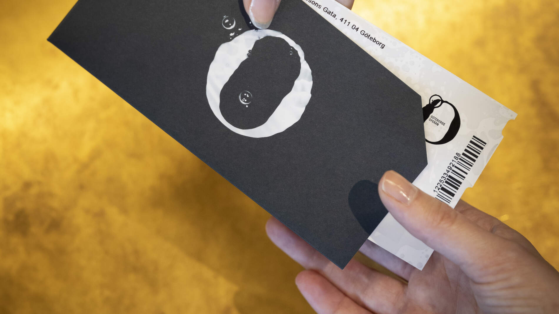 Närbild av en hand som skickar biljetter över biljettkassa disken till en annan hand.