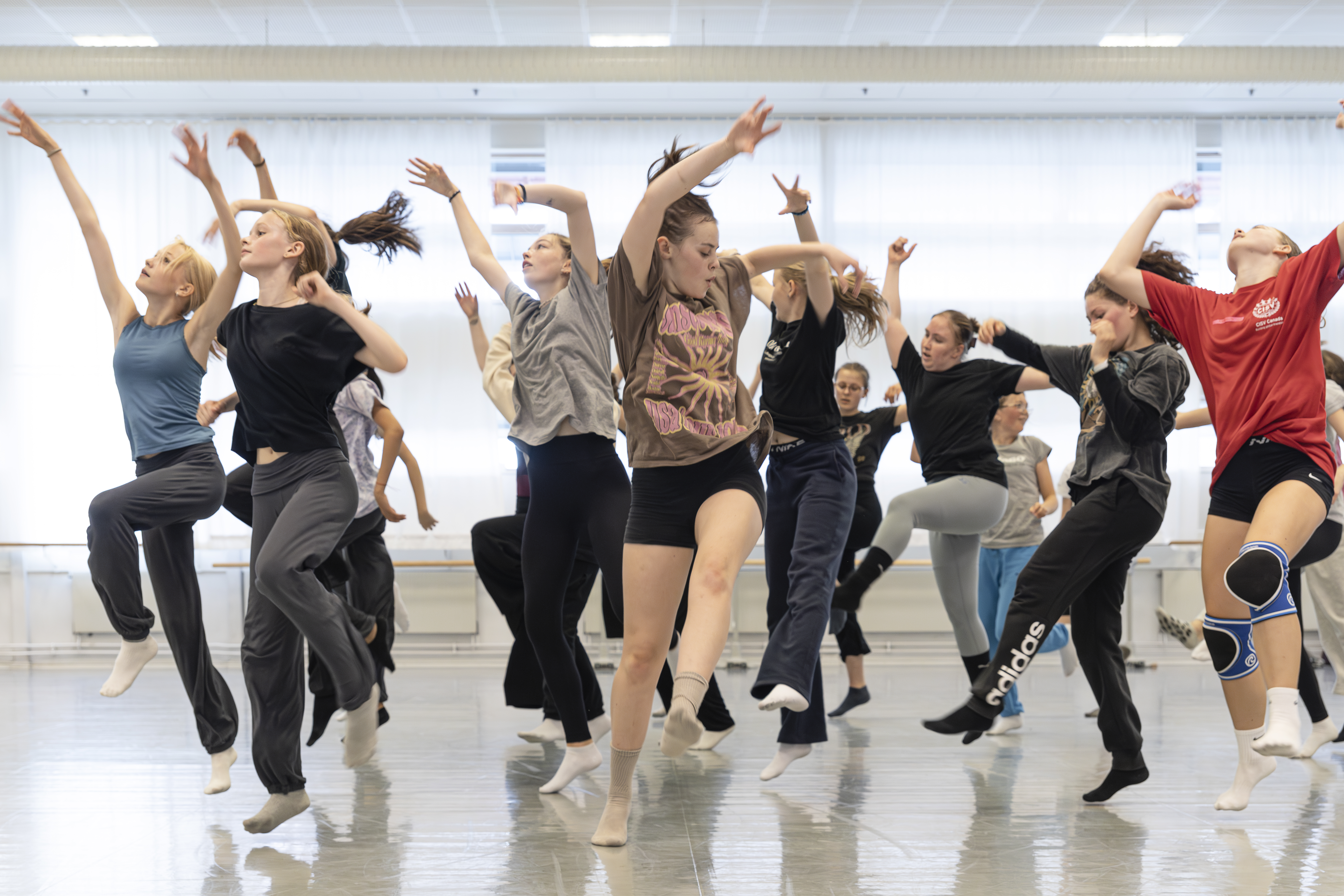 En grupp unga människor dansar energetiskt i en dansstudio.