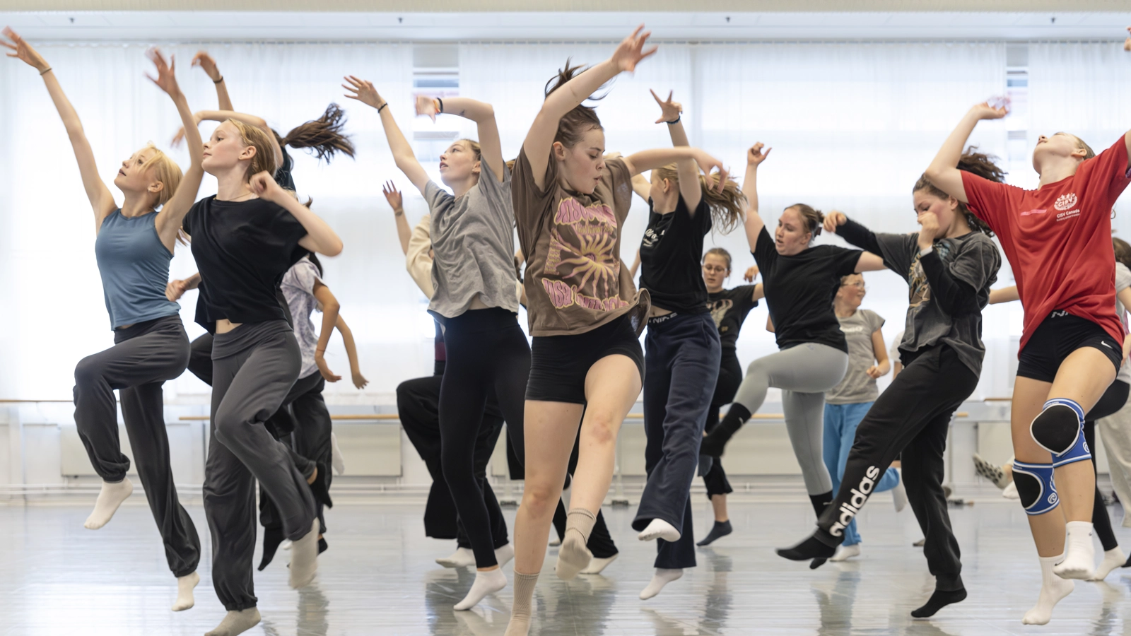 En grupp unga människor dansar energetiskt i en dansstudio.