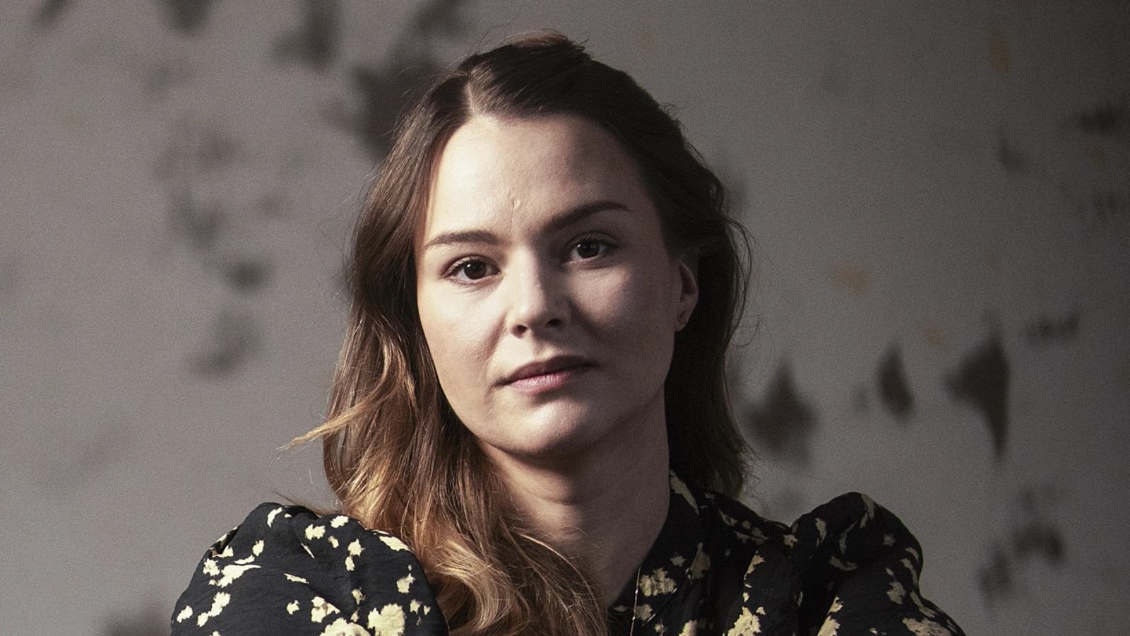 En operasolist sitter på en trästol med underarmarna mot ryggstödet och högerfoten uppdragen på stolen. Hon är barfota.