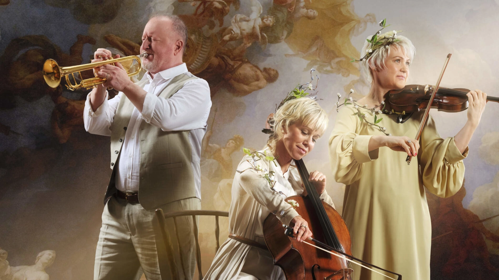 En cellist, violast och trumpetist spelar sina instrument mot en målad barockbakgrund. Två har lövkransar i håret.