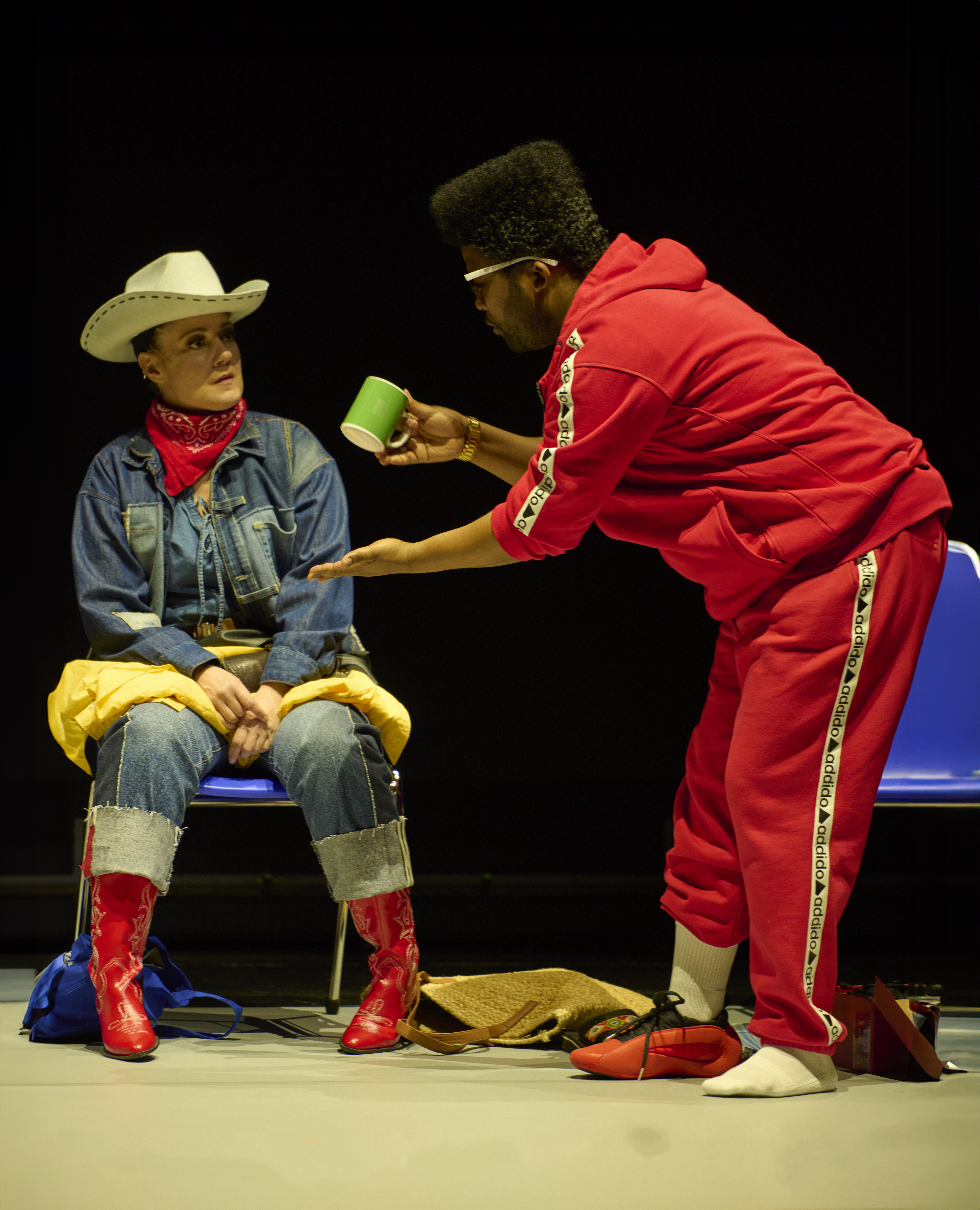 Nelson lutar sig fram och erbjuder en grön kaffemugg till Clara som har en cowboyhatt på huvudet.