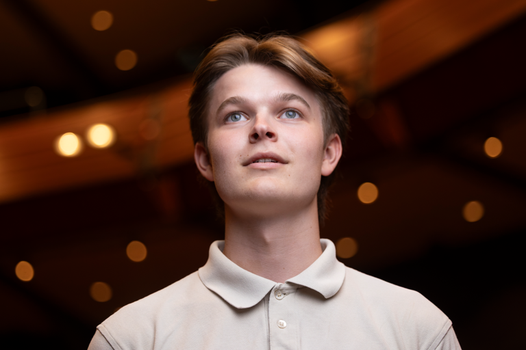 En ungdom i teatersalong betraktar vad som sker på scen med ett förtjust ansiktsuttryck.