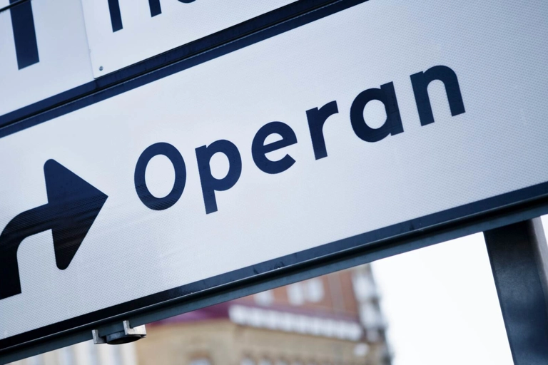 Närbild av en stadsgatuskylt som visar en pil som pekar mot "Operan".