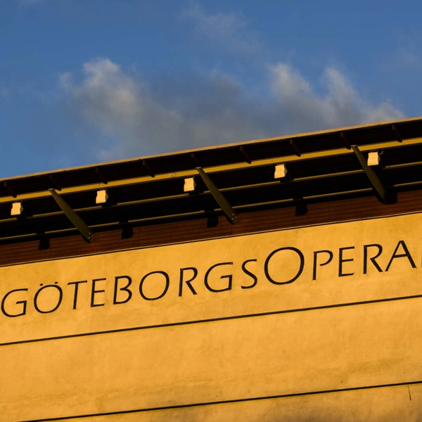 Översta delen av Göteborgsoperans fasad, upplyst i morgonsolen. Ordet "GöteborgsOperan" syns skrivet på fasaden.